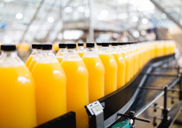 Bottling factory - Orange juice bottling line for processing and bottling juice into bottles. Selective focus.