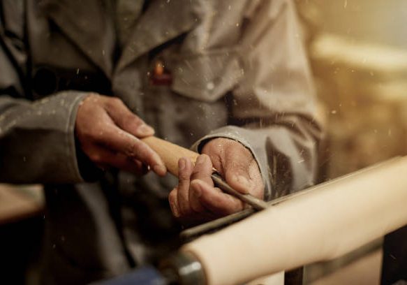 Cropped shot of an unrecognizable male carpenter chiselling away on a piece of wood in his workshop